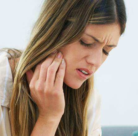 woman holding her jaw in pain